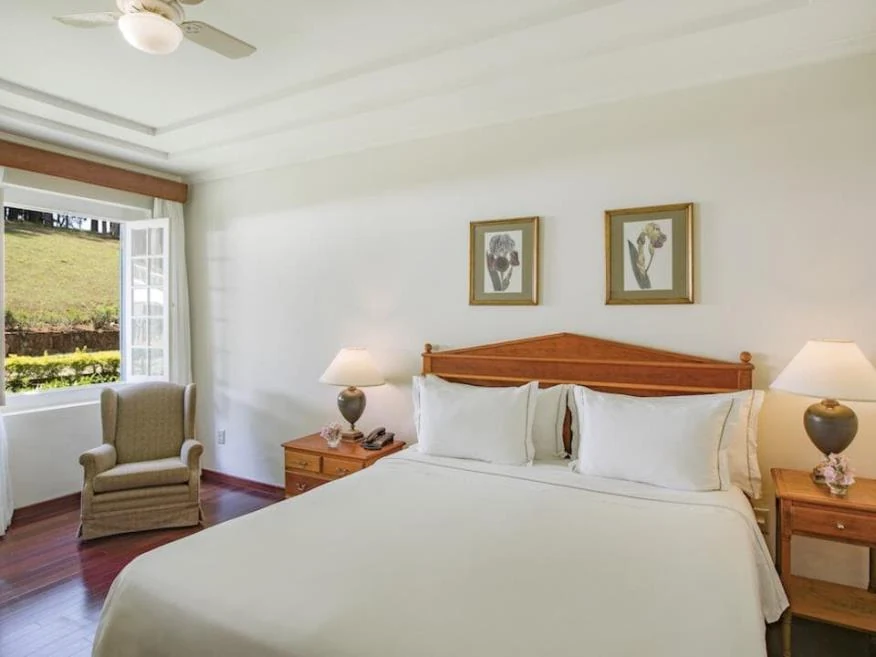 Quarto com cama de casal e janela para o jardim, categoria Luxo do Hotel Fazenda Dona Carolina
